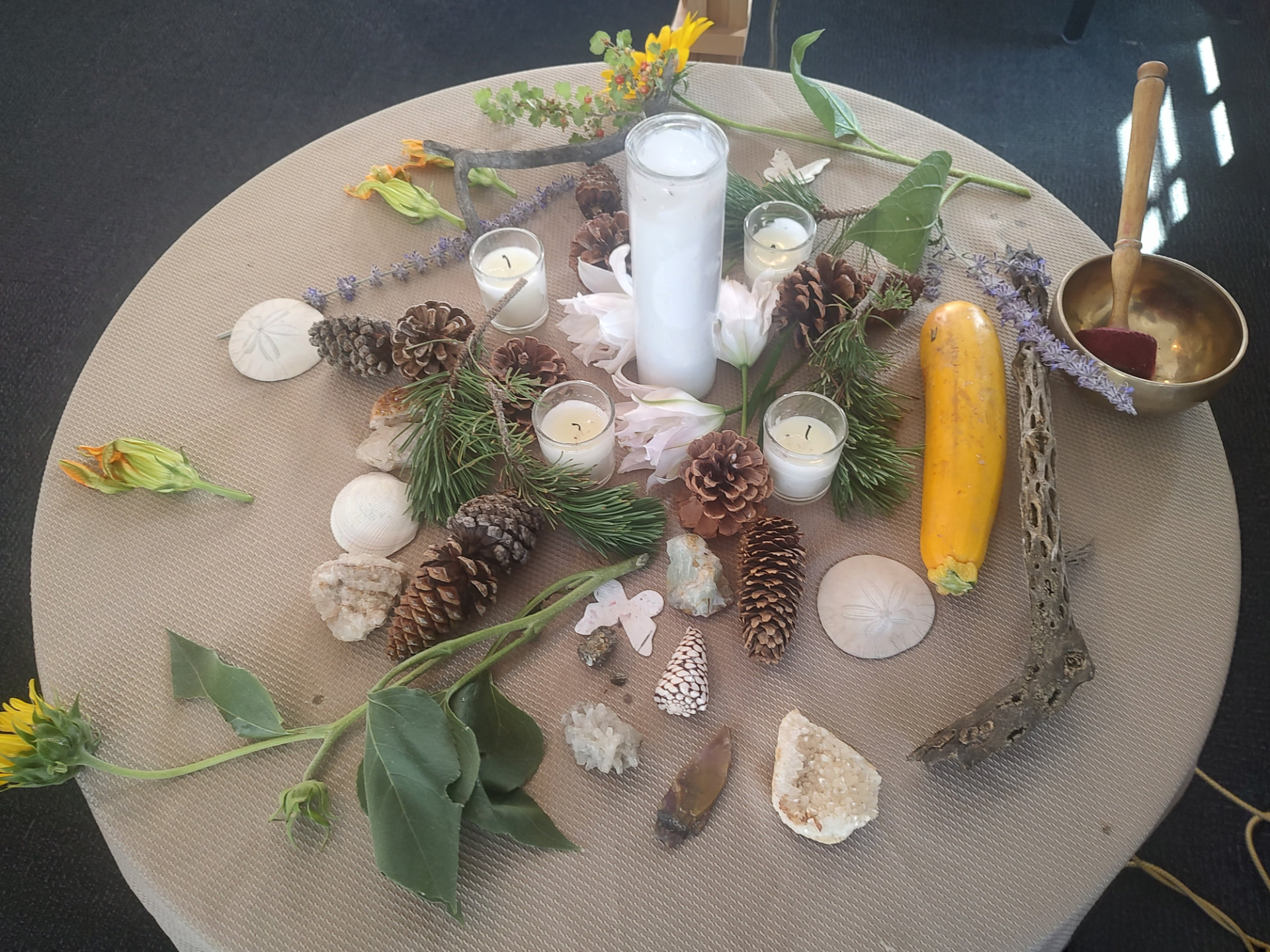 A round altar of candles, pine boughs, shells, crystals and a brass singing bowl