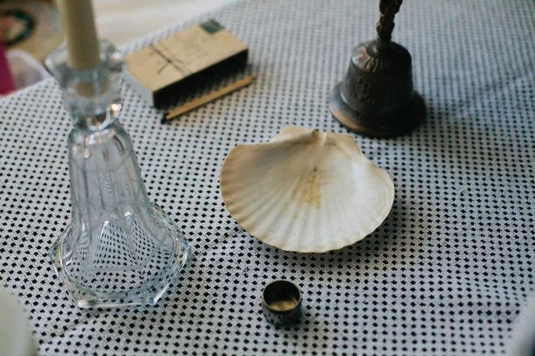 A christening shell, candle, bell and small bowl arranged on a table