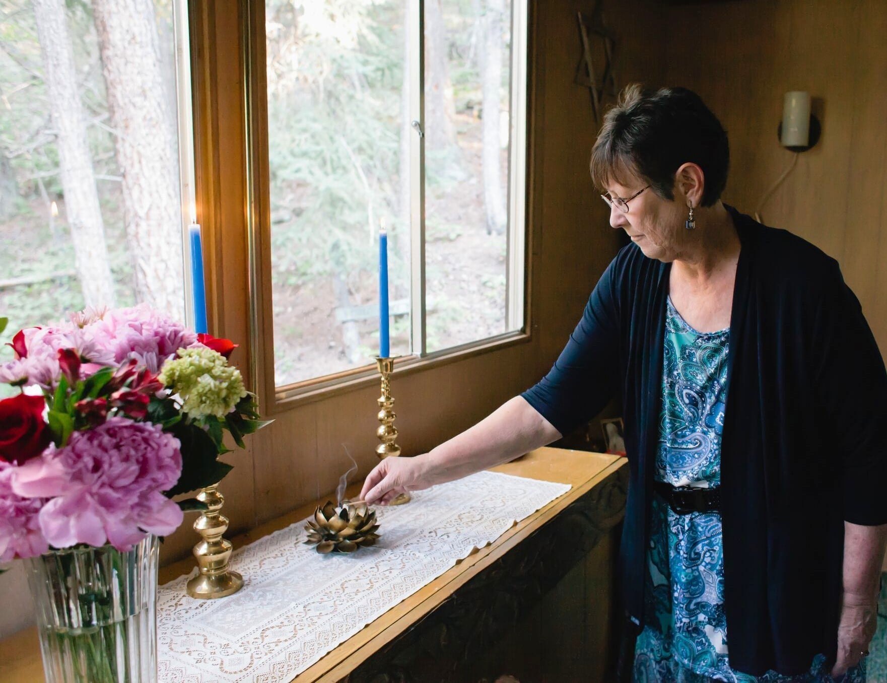 Teri Martin lighting incense beside candles and flowers